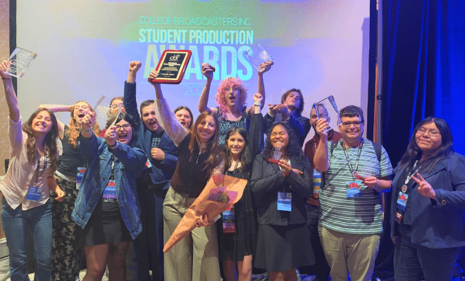 Group photo of students at the CBI Awards, cheering, smiling, and raising their awards.