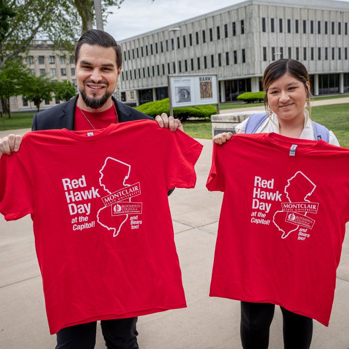 A man and a woman hold up their Red Hawk Day t-shirts.