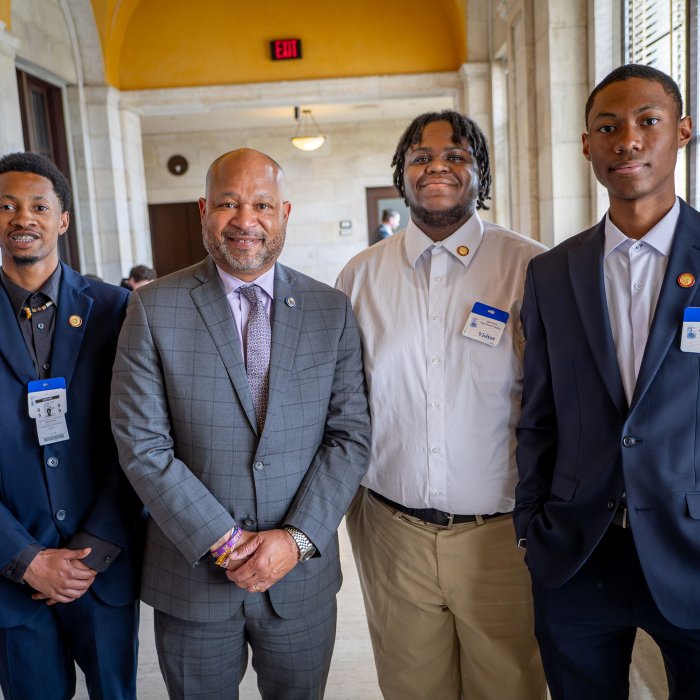 Three young men and a legislator pose for a picture.