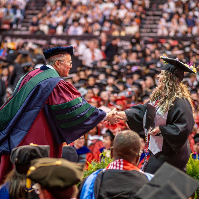 Provost Gonzales shakes hands with a graduate