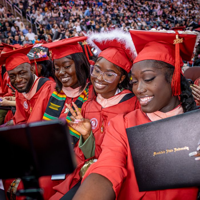 group of four graduates pose for a selfie