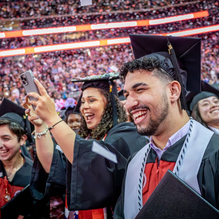 graduates smiling and taking photos as confetti falls