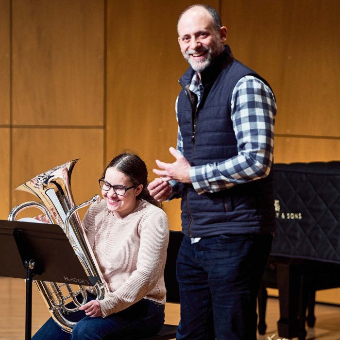 Female student with an instrument that looks like a small tuba with male professor.