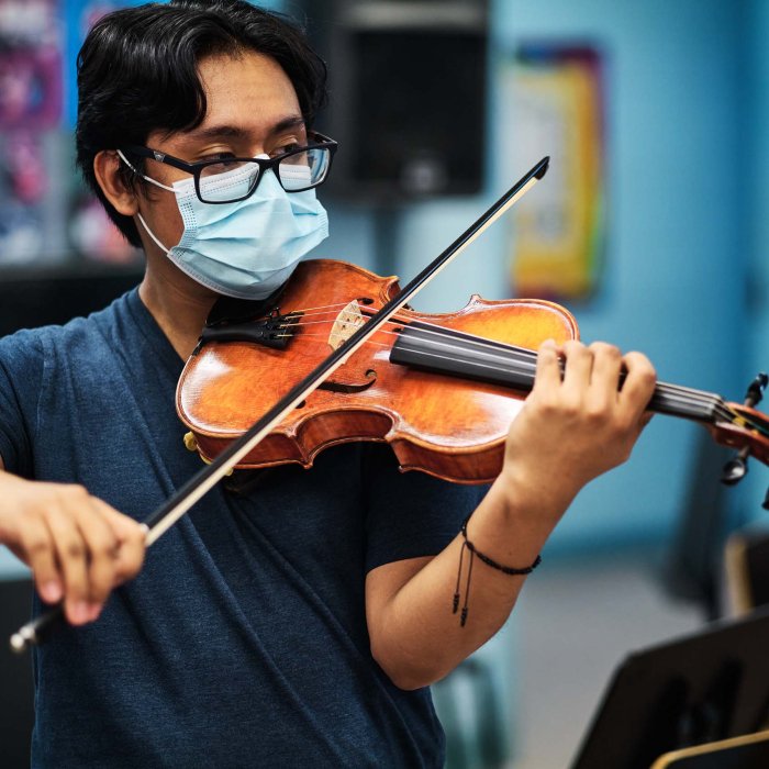 A young man plays a violin.
