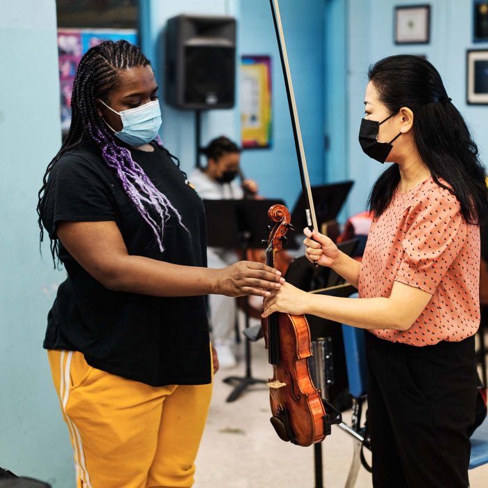 Two women hold a violin.