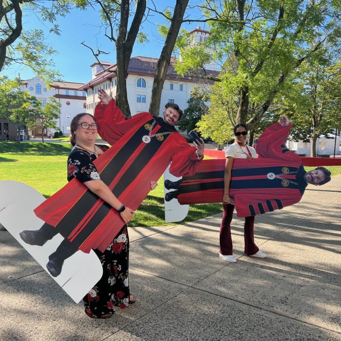 two ambassadors carrying cardboard cutouts of President Koppell