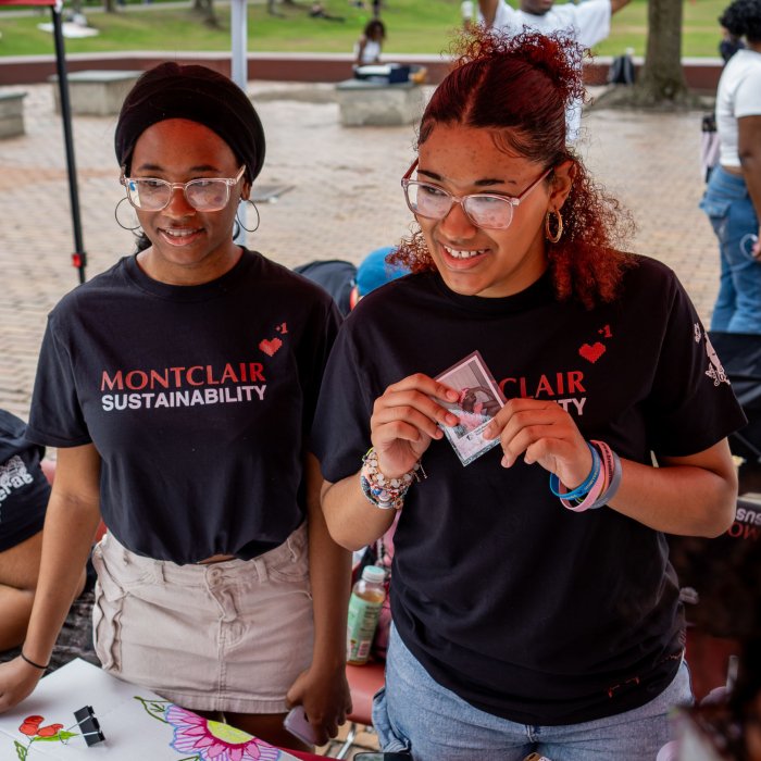 Two female presenting students running an Earth Day table activity.