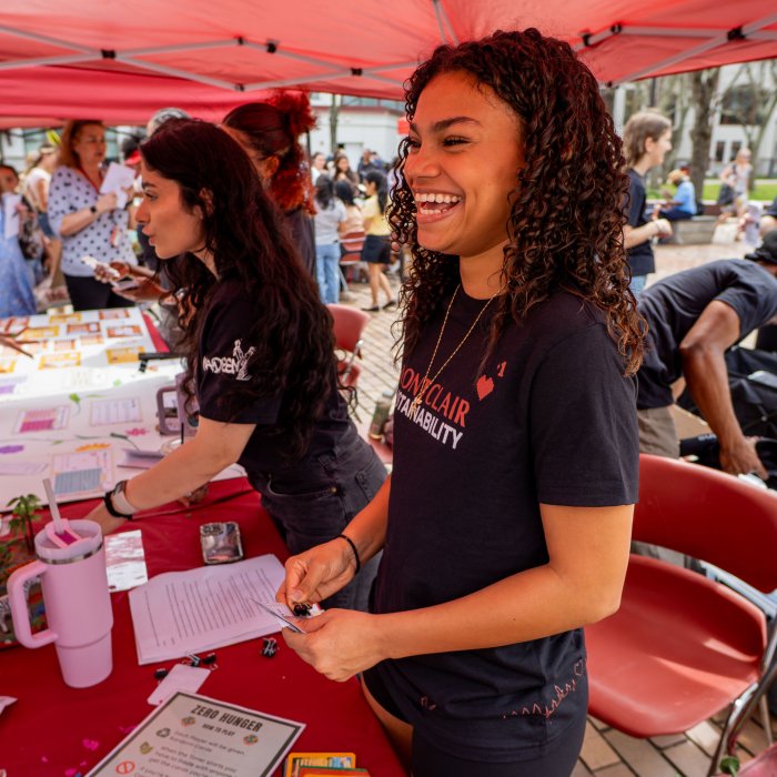 Student intern laughing while running a table activity at Earth Day 2026.
