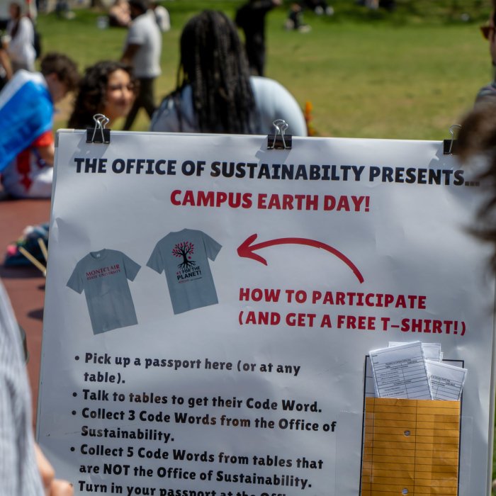 Photo of the instructions for the Campus Earth Day Passport activity with students on the quad in the background.