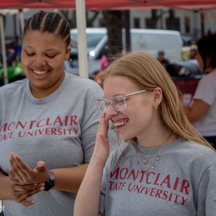 Two female presenting students laughing while working at the 2025 Earth Day event.