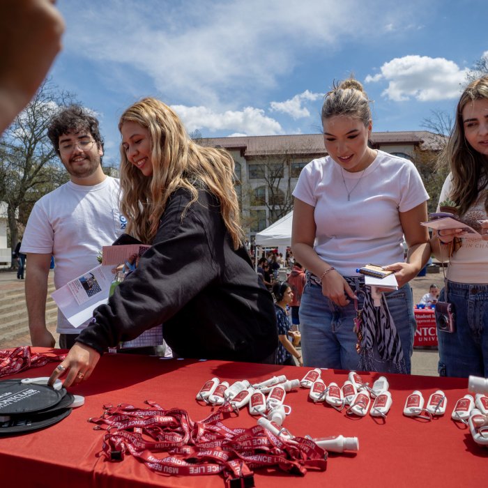 A group of students at an Earth Day table looking at giveaway items.