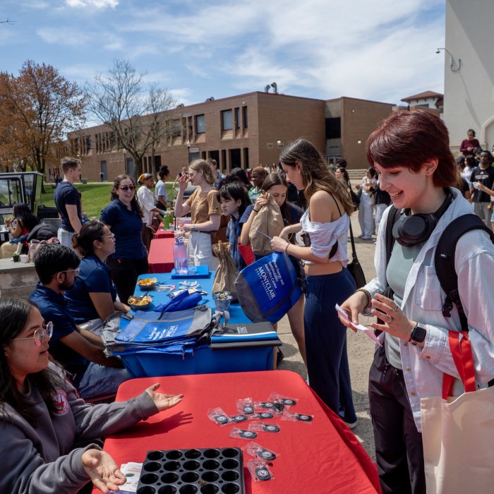 Photo of some of the tables set up in the Student Center Quad for the 2025 Earth Day event with students participating in activities and milling around.