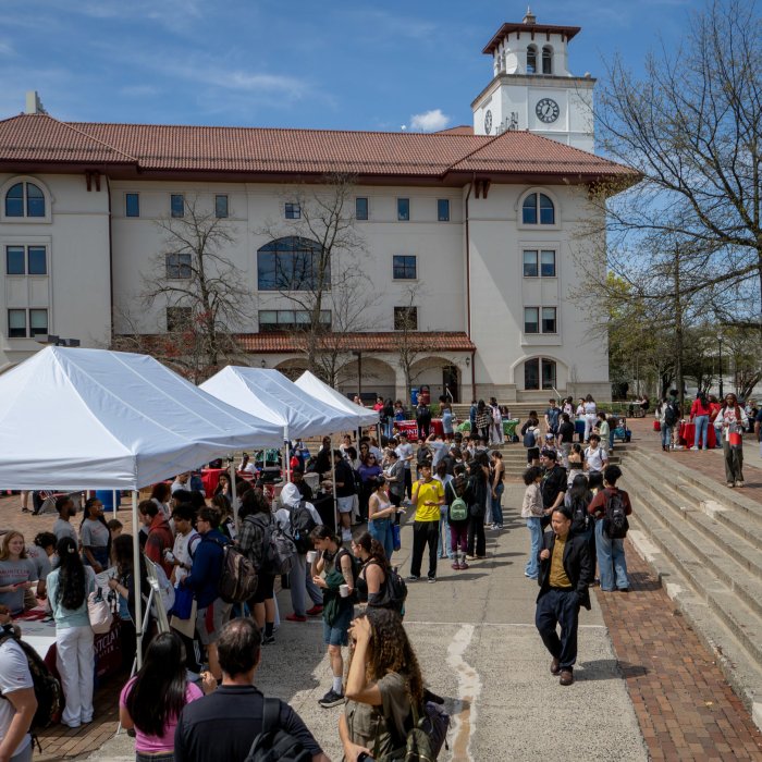 Photo of some of the tables set up in the Student Center Quad for the 2025 Earth Day event with students participating in activities and milling around.