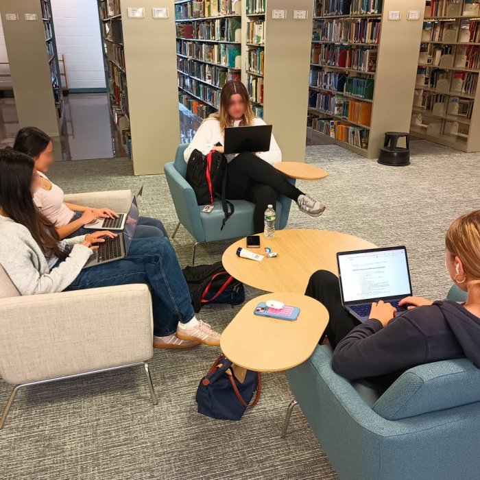 two students sitting on a couch and two chairs with laptops