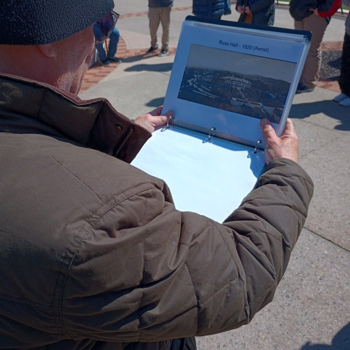 group standing in from of morehead hall with two people viewing a binder