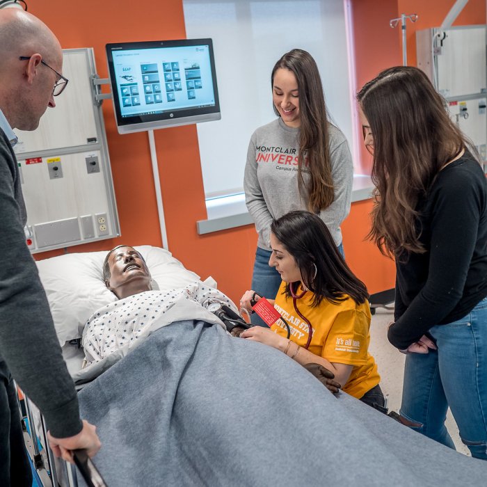Students and faculty standing around a patient care manikin.