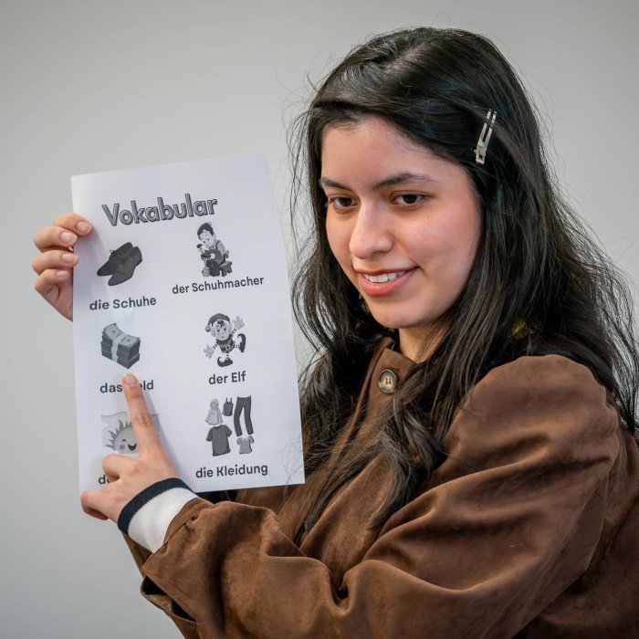 A woman holds up a paper with several German words written