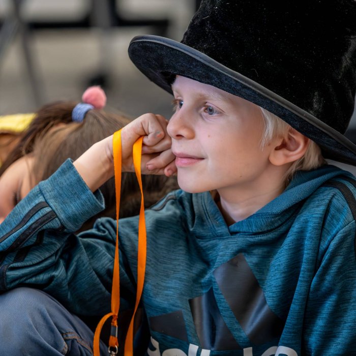 A young boy sits on the floor wearing a top hat