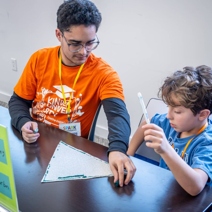 An adult helps a child work on an art activity