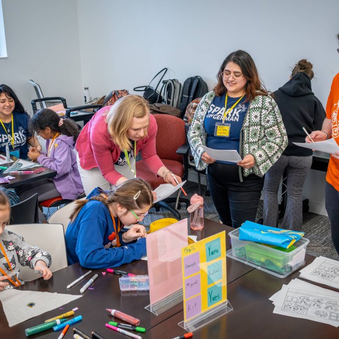 Three adults help children work on art activities at a desk