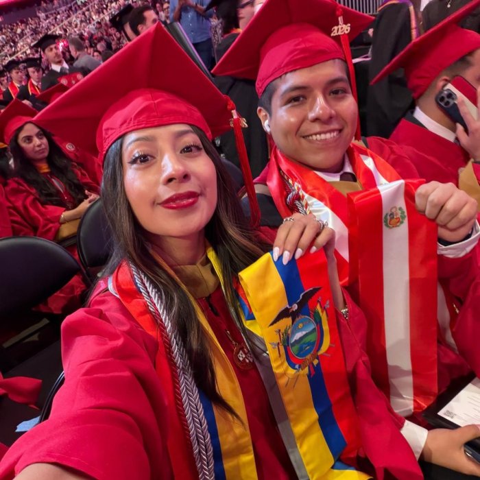 A picture of two students wearing their Montclair graduation gear and holding up their stoles.