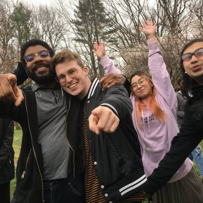 A group of four college students pose outside in a group for a photo