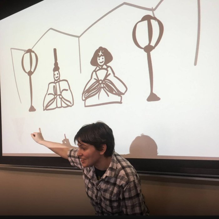 A person gestures toward a projection screen during a presentation
