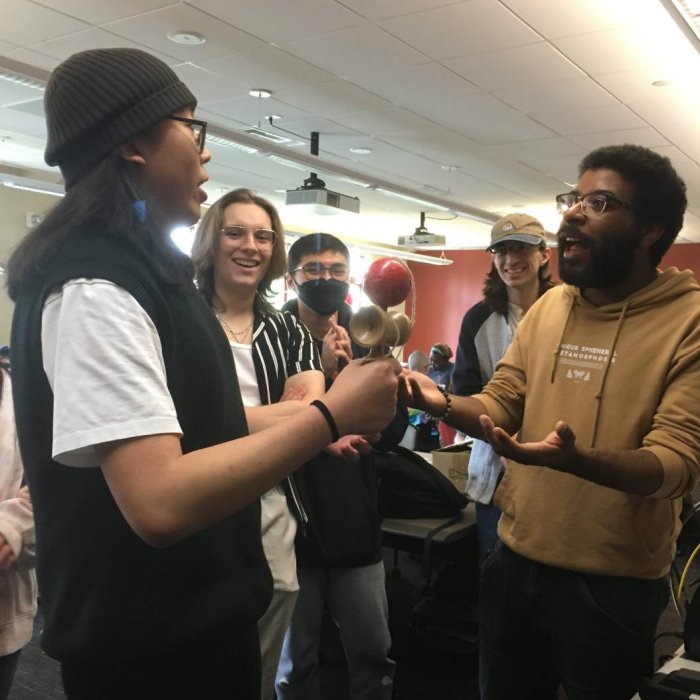 Several people stand together and appear to be speaking as an audience watches