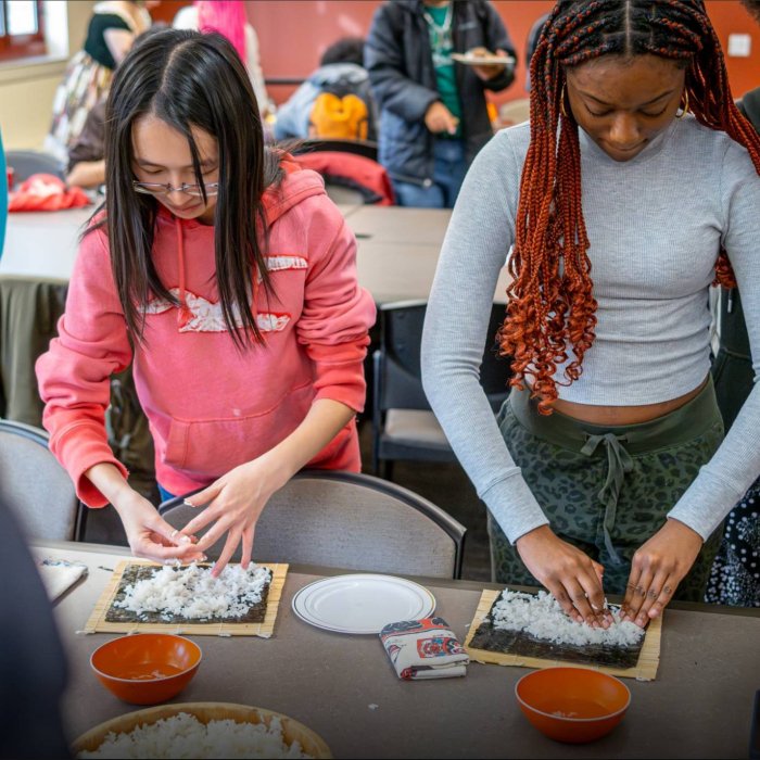  Two college students prepare sushi rolls