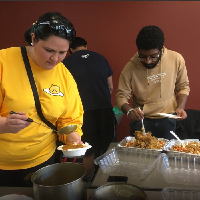 Two college students scoop food from a buffet onto their plates