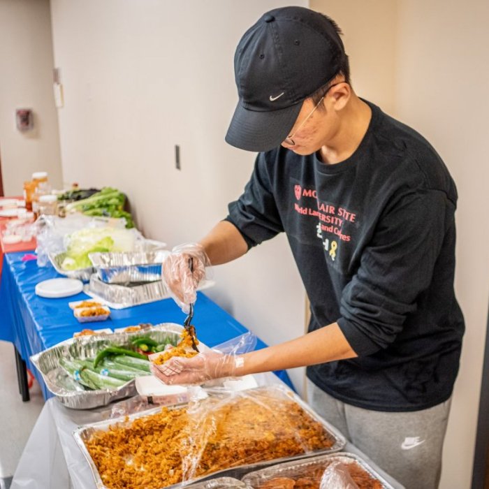 A man serves kimchi from a buffet line into a paper bowl