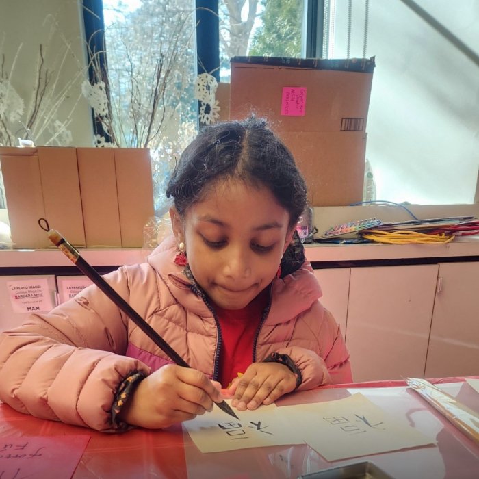 A child writes the Chinese character 福 which means fortune