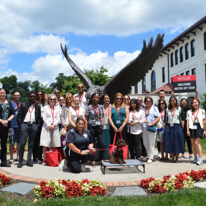 A picture of a group of counselors at the Metro New York Tour. Pebbles is in front and the Red Hawk statue is in the back.