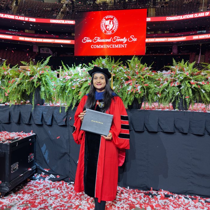 A picture of a student at commencement, holding their diploma.