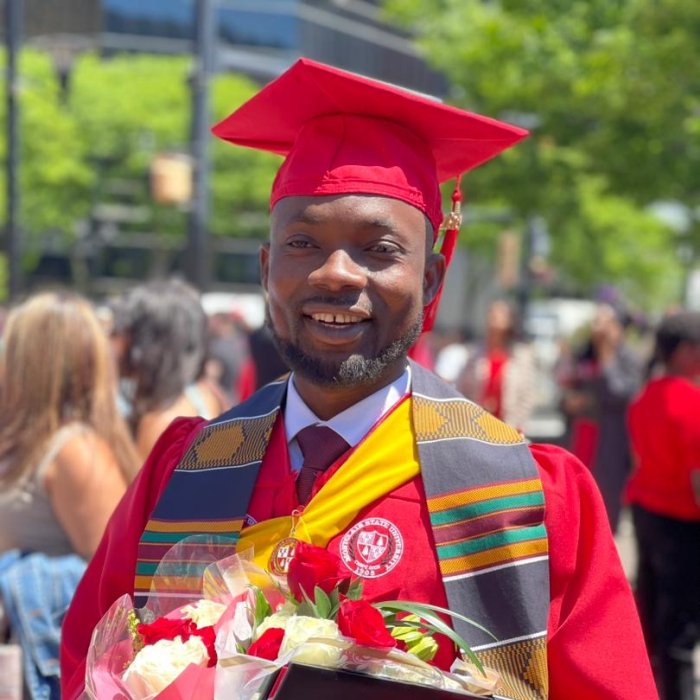 A picture of a Montclair student in their graduation gear and holding flowers and their diploma.