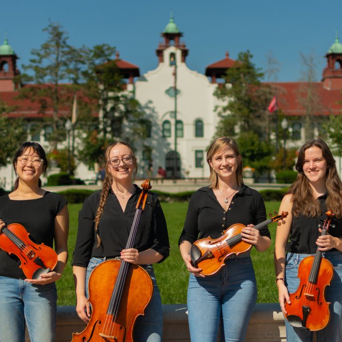 String Quartet standing in front of Susan Cole Hall at Montclair State University