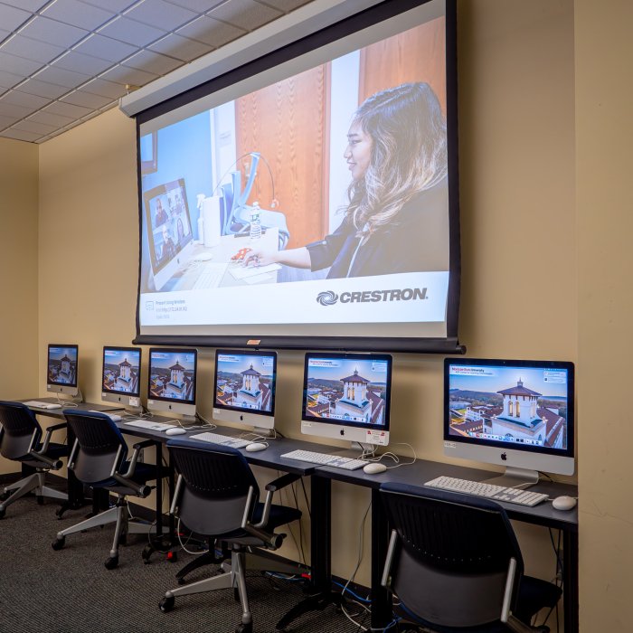 Wall of computer lab with projector screen above computers