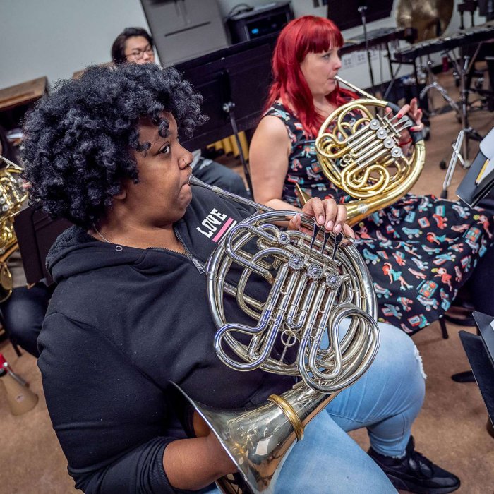 Three French horn players in rehearsal