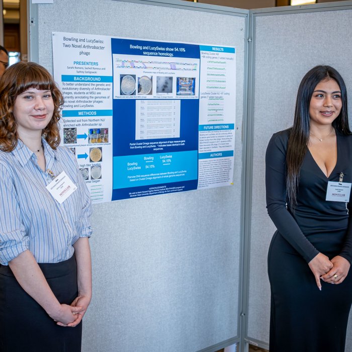 Students smiling next to their poster