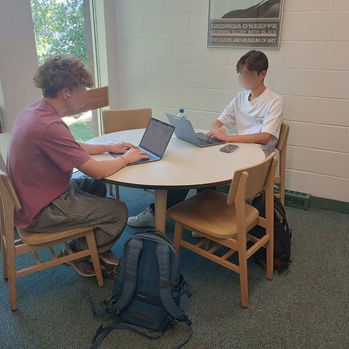 2 students sitting at a table on laptops