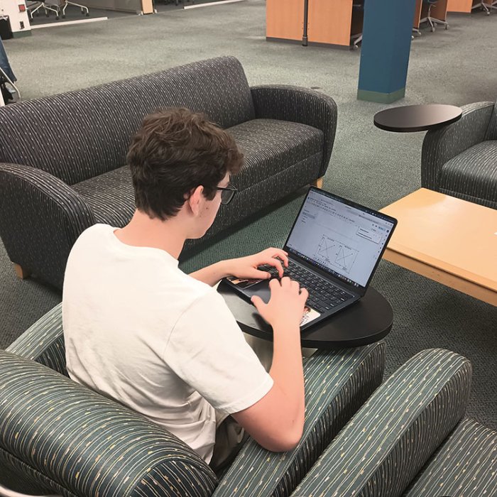 student sitting at a laptop researching