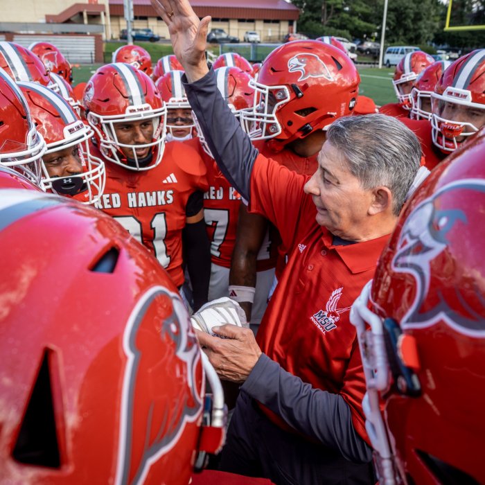 Football players surrounding coach