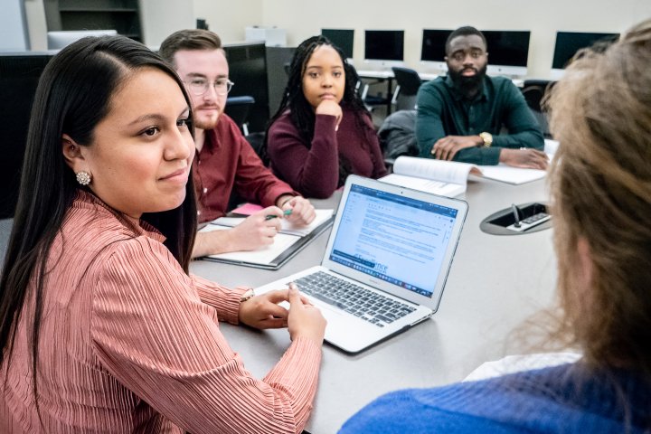 a group of students work around a computer