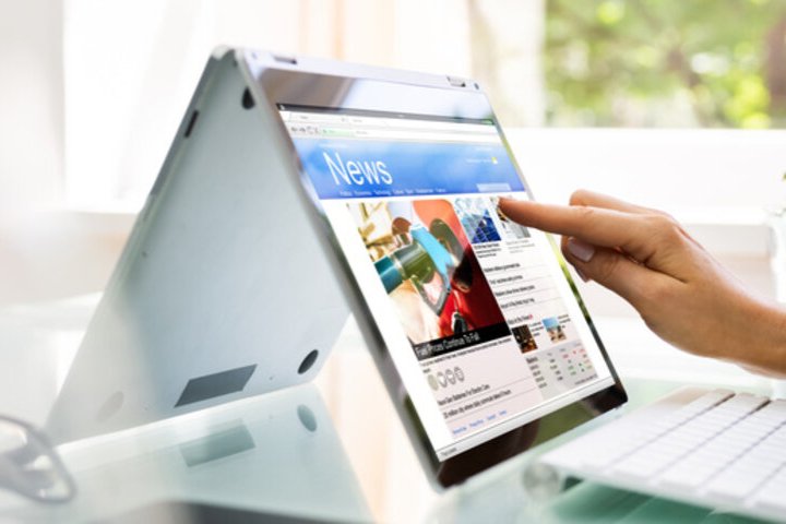 A convertible tablet displaying a news webpage.