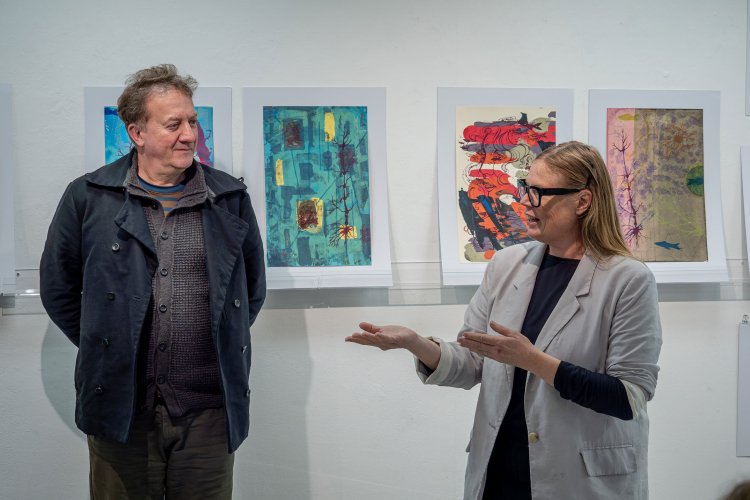 Thomas Mueller and Jennifer Wroblewsk stand before student artwork.