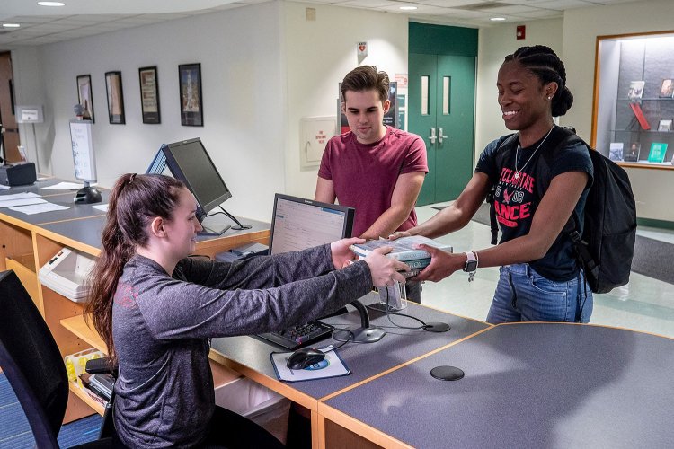 students checking out a book at front desk
