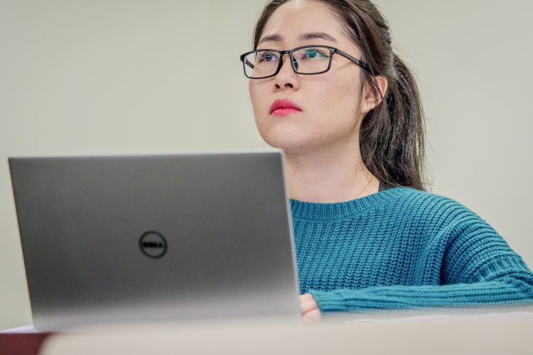 Student in a class behind a laptop
