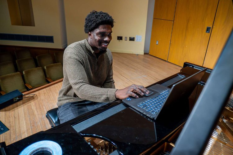 Student on stage at piano with computer