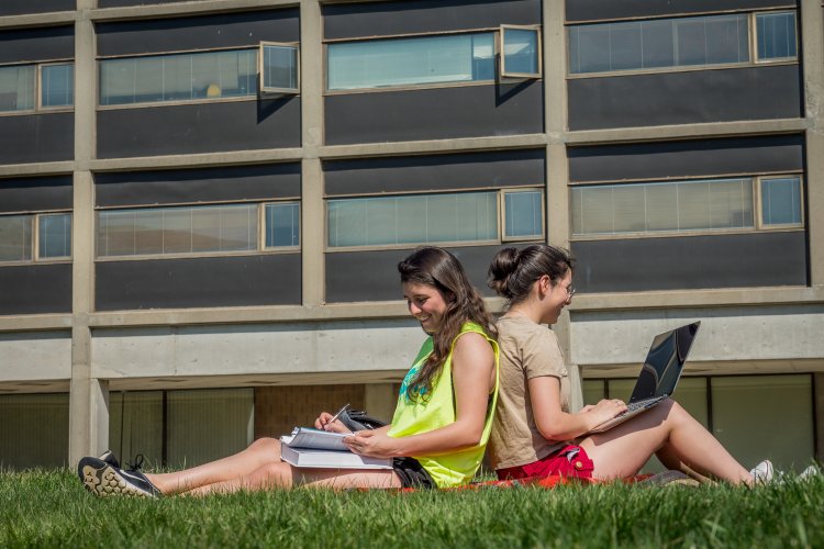 two students studying back to back outside