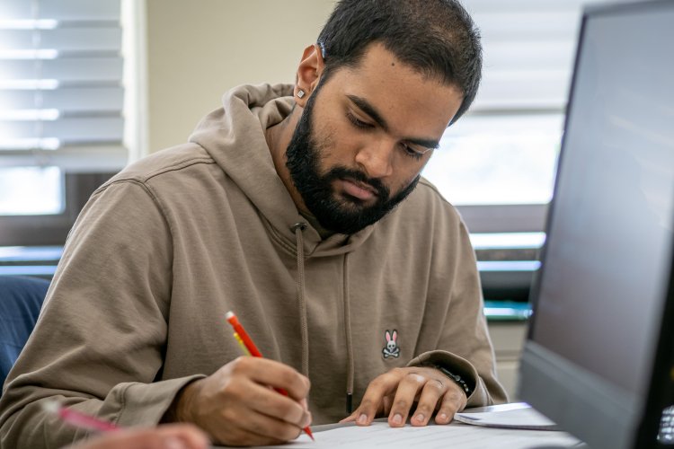 Male student writing near a computer screen